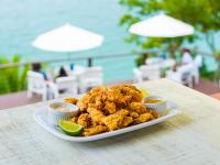 a plate of fried food on a table with condiments at Barra do Piuva Porto Hotel in Ilhabela