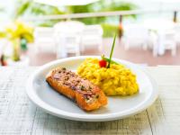 a white plate with a piece of fish and scrambled eggs at Barra do Piuva Porto Hotel in Ilhabela