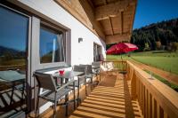 a deck with a table and chairs and a red umbrella at Gästehaus Hain in Hochfilzen