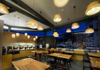 a restaurant with wooden tables and chairs and lights at Yunoyado Onsen Hot Spring Hotel -Xinyi Branch in Jiaoxi