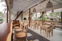 a restaurant with wooden tables and chairs and windows at Sadev Resort in Gili Trawangan