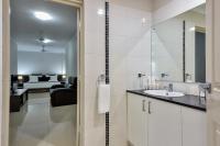 a bathroom with a sink and a bedroom at Argus Apartments Darwin in Darwin