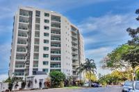 a tall white apartment building on a street at Argus Apartments Darwin in Darwin