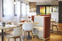 ein Restaurant mit weißen Tischen und weißen Stühlen in der Unterkunft Kyriad Paris Ouest - Bezons La Défense in Bezons