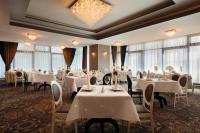 a restaurant with white tables and chairs and windows at Ramada by Wyndham Constanta in Constanţa