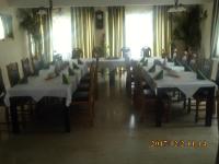 a dining room with white tables and chairs and windows at Pension Balkan in Eisenhüttenstadt