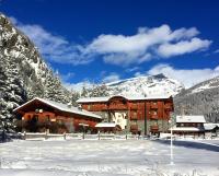 a large building in the snow with snow covered mountains at Le Rocher Hotel in Champoluc