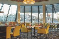 um restaurante com cadeiras amarelas, mesas e janelas em H4 Hotel Hannover Messe, Trademark Collection by Wyndham em Hanôver