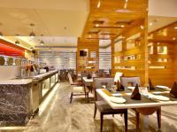 Un restaurante con mesas y sillas y un bar. en Regenta Central the Crystal Kanpur,, en Kānpur