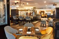 Un restaurante con mesas y sillas y un bar. en Steigenberger Icon Frankfurter Hof, en Frankfurt