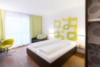 a bedroom with a large bed and a yellow chair at arte Hotel Krems in Krems an der Donau