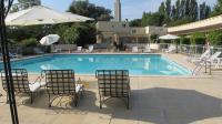 una piscina con dos sillas y una sombrilla en Hôtel Acostel, en Meaux