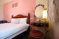 a bedroom with a bed and a mirror and a stool at Dear B&amp;B in Hualien City