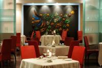 a dining room with tables and chairs and a wall with a flower mural at Mare Hotel in Savona