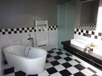 a bathroom with a large tub and two sinks at Villa Élyane in Colmar