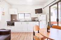 a kitchen with white cabinets and a table with a bottle of wine at Lorne Foreshore Caravan Park in Lorne
