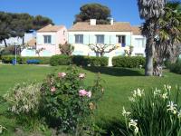 a large white house with pink flowers in a yard at Village Club Thalassa in Mèze