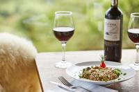 een tafel met een bord eten en een fles wijn bij Villa Bella Hotel & SPA Gramado in Gramado