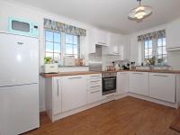 a kitchen with white cabinets and a white refrigerator at Omalast in Truro