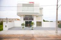 un edificio blanco con dos palmeras delante en Hotel Portal Guanambi, en Guanambi
