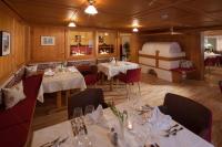 a restaurant with white tables and chairs and a bed at Hotel Kanisfluh in Mellau