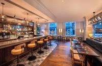 a restaurant with a bar and tables and chairs at Leonardo Hotel Cardiff in Cardiff