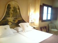 a bedroom with a white bed with a painting on the wall at Sacristia de Santa Ana in Seville