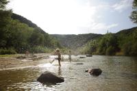 two people and a dog standing in a river at Camping La Bohème in Tournon-sur-Rhône