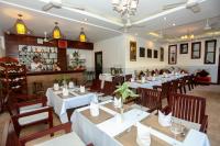un restaurante con mesas blancas y sillas de madera en The Moon Residence & Spa, en Siem Reap
