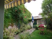 a garden with a umbrella and a table and chairs at Gite chez Cyrano in Bergerac
