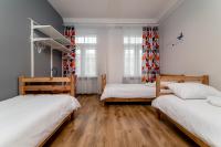two beds in a room with wooden floors and windows at Orange Cat Rooms in Riga