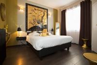 a bedroom with a large bed with a painting on the wall at Hôtel Mademoiselle in Juan-les-Pins