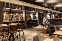 Un bar con mesas de madera y taburetes. en Revier Mountain Lodge Lenzerheide, en Lenzerheide