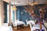 une salle à manger avec des tables et des chaises blanches et un mur bleu dans l'établissement Hotel Kasteel Doenrade, à Doenrade