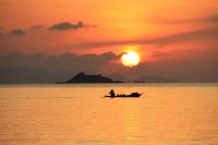 a man in a boat in the ocean at sunset at Nice Sea Resort in Srithanu