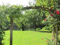 an archway in a field with roses at La Minoterie in Tessy-sur-Vire