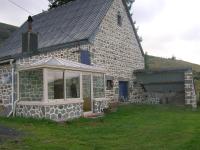 a stone house with a large window in a yard at le monne (dit la fermette ) in Chambon-sur-Lac