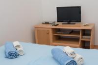 a bed with towels and a desk with a television at Rooms Vendi in Daruvar