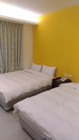 two beds in a room with a yellow wall at Galaxy Mini Inn in Taipei