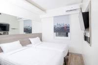 a white bedroom with a bed and a tv at Red Planet Manila Bay in Manila
