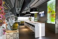 a restaurant with a long bar with yellow chairs at Tulip Inn Eindhoven Airport in Eindhoven