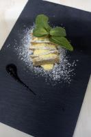 a black plate with a sandwich with a green leaf on it at Hotel Classensis in Ravenna