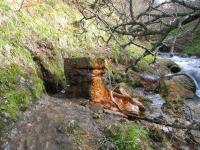 a stream of water coming out of a stone bridge at le monne (dit la fermette ) in Chambon-sur-Lac