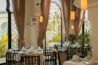 een restaurant met witte tafels en stoelen en een groot raam bij Sarai and Wander Resort in Siem Reap