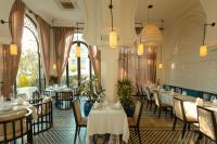 een restaurant met witte tafels, stoelen en ramen bij Sarai and Wander Resort in Siem Reap