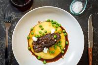 a plate of food with meat and peas on a table at Fable Auckland, MGallery in Auckland