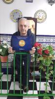 a man sitting in a chair with a laptop at Pensión San Benito Abad in Seville