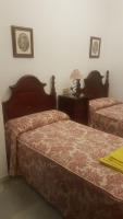 a bedroom with two beds and a table with a lamp at Pensión San Benito Abad in Seville