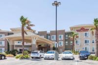 a parking lot in front of a hotel with parked cars at Hawthorn Suites in Victorville