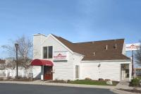 Un edificio blanco con un toldo rojo en una calle. en Hawthorn Extended Stay by Wyndham Fort Wayne, en Fort Wayne